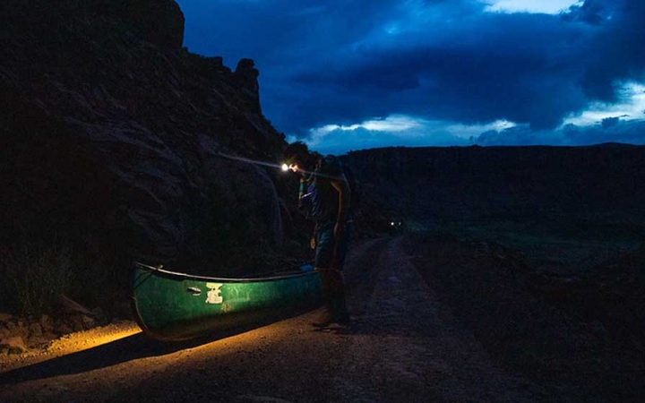 a student wearing a headlamp illuminates a canoe on an outward bound expedition 
